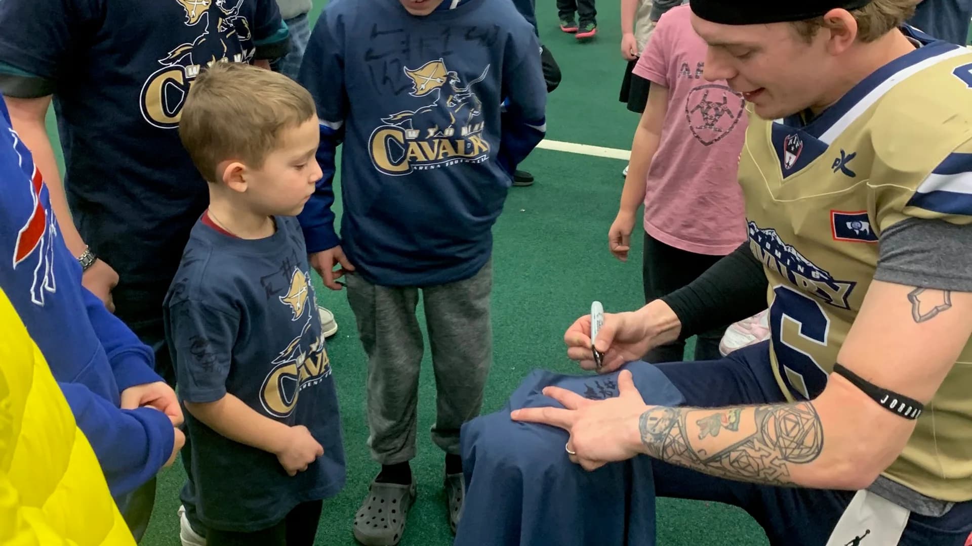 Matt Laur signing gear for young football fans after a game